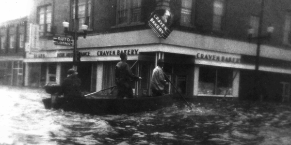 black and white photo of people in a boat on a flooded street in downtown New Bern in 1955